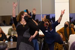 Three folks posing with their arms in the air.