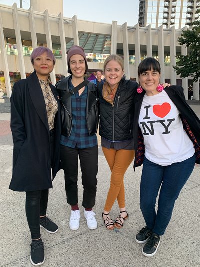 Photo of Guild staff (left to right) Rangsey Keo, Jenina Podulka, Heather Ikemire, and Ivy Young smiling and standing in front of the Emma S. Barrientos Mexican American Cultural Center