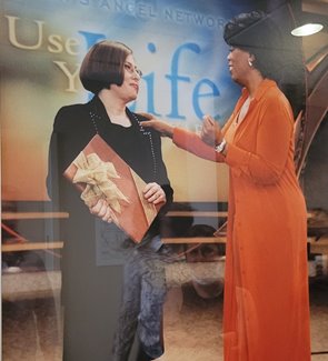 Duffie Adelson on stage at the Oprah Winfrey show, with Oprah facing her with her hand on her shoulder.