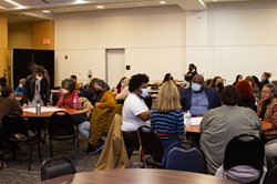 A photo of six round tables, each with folks working together.